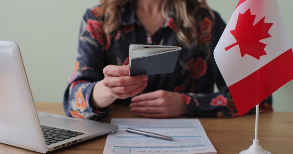 A woman handing a Canadian passport with the Canadian flag on the side