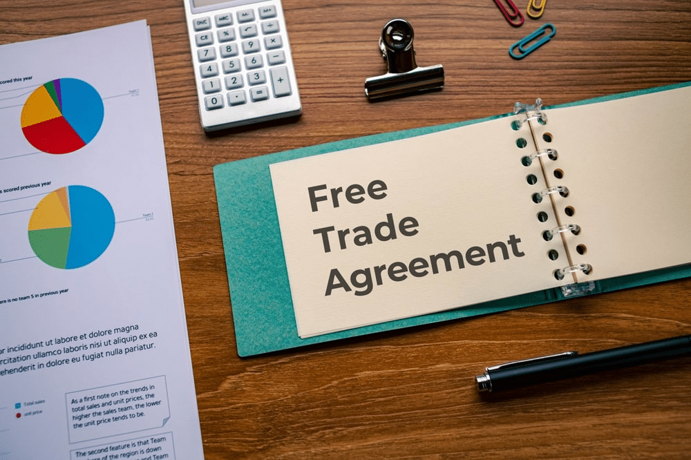 A pie chart on the left and a notebook on the right with text "Free Trade Agreement"