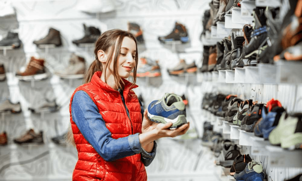 A girl holding a shoe while in a shoe store.