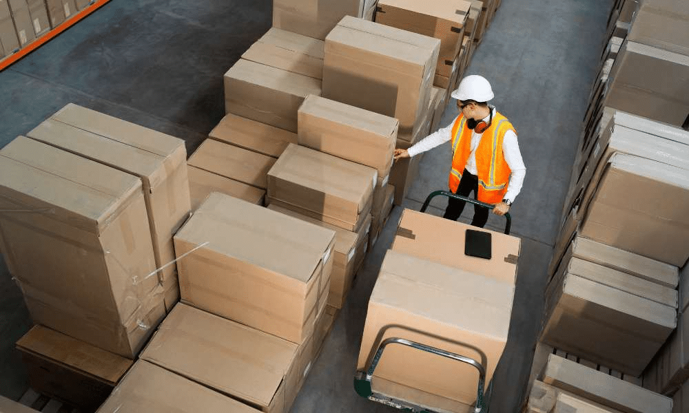 A man checking boxes in a warehouse.