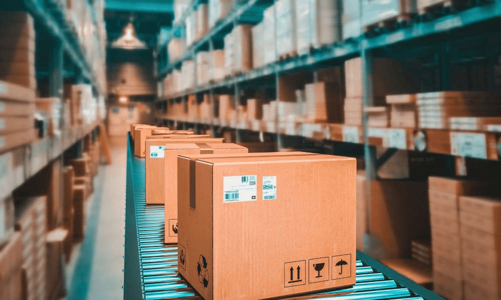 Cardboard boxes on a conveyor belt in a warehouse.