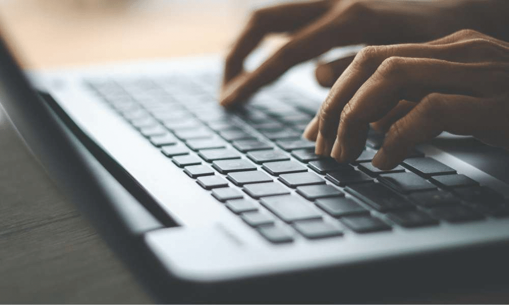 Close-up of hands typing on a laptop keyboard.