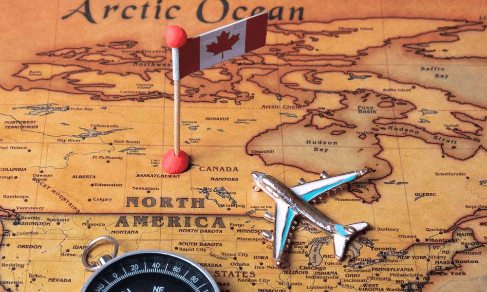 Map of North America with a Canadian flag pin, plane toy, and a compass.