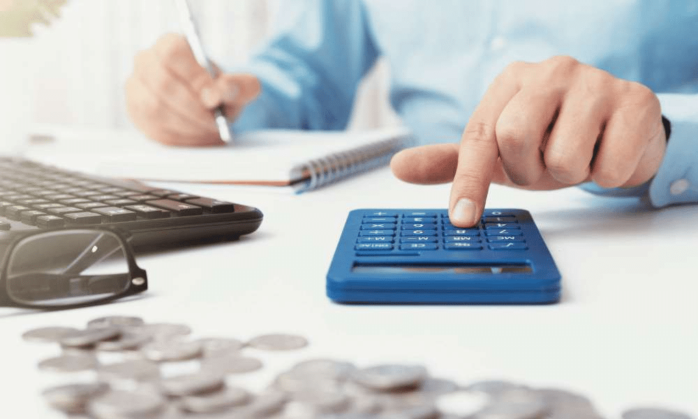 Person using a calculator next to a keyboard.