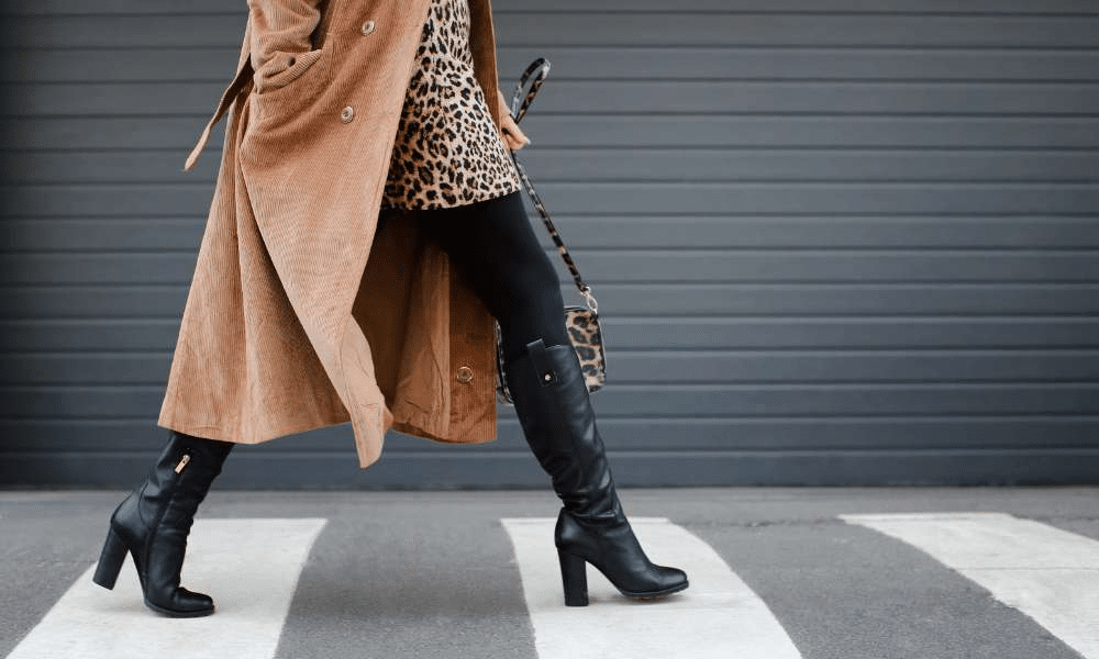 Woman in high-heeled boots and stylish coat walking on a crossing.