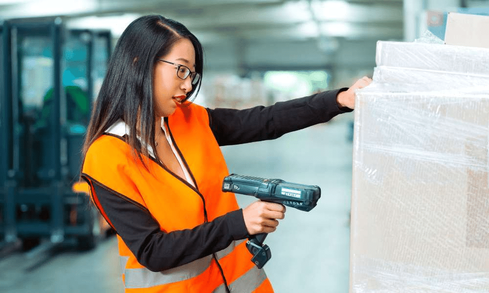 Worker in a vest using a barcode scanner on a pallet.